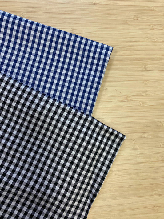 Photo of 2 different colours of  Classical Tencel Check fabric folded and stacked. photographed from above on a wooden table.