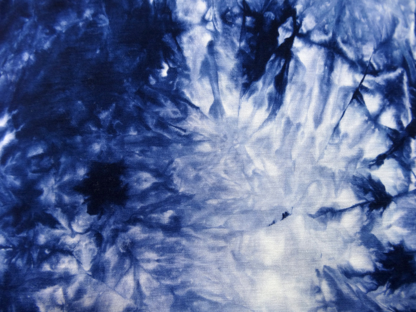 A deep navy blue to white tie dyed fabric laid flat