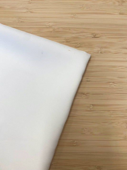 A piece of folded white chiffon fabric photographed from above on a wooden table