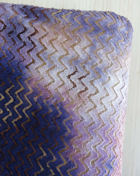 tie dye zigzag jacquard fabric. Colours in blues, purples and pink tones,  folded and photographed on a wooden table