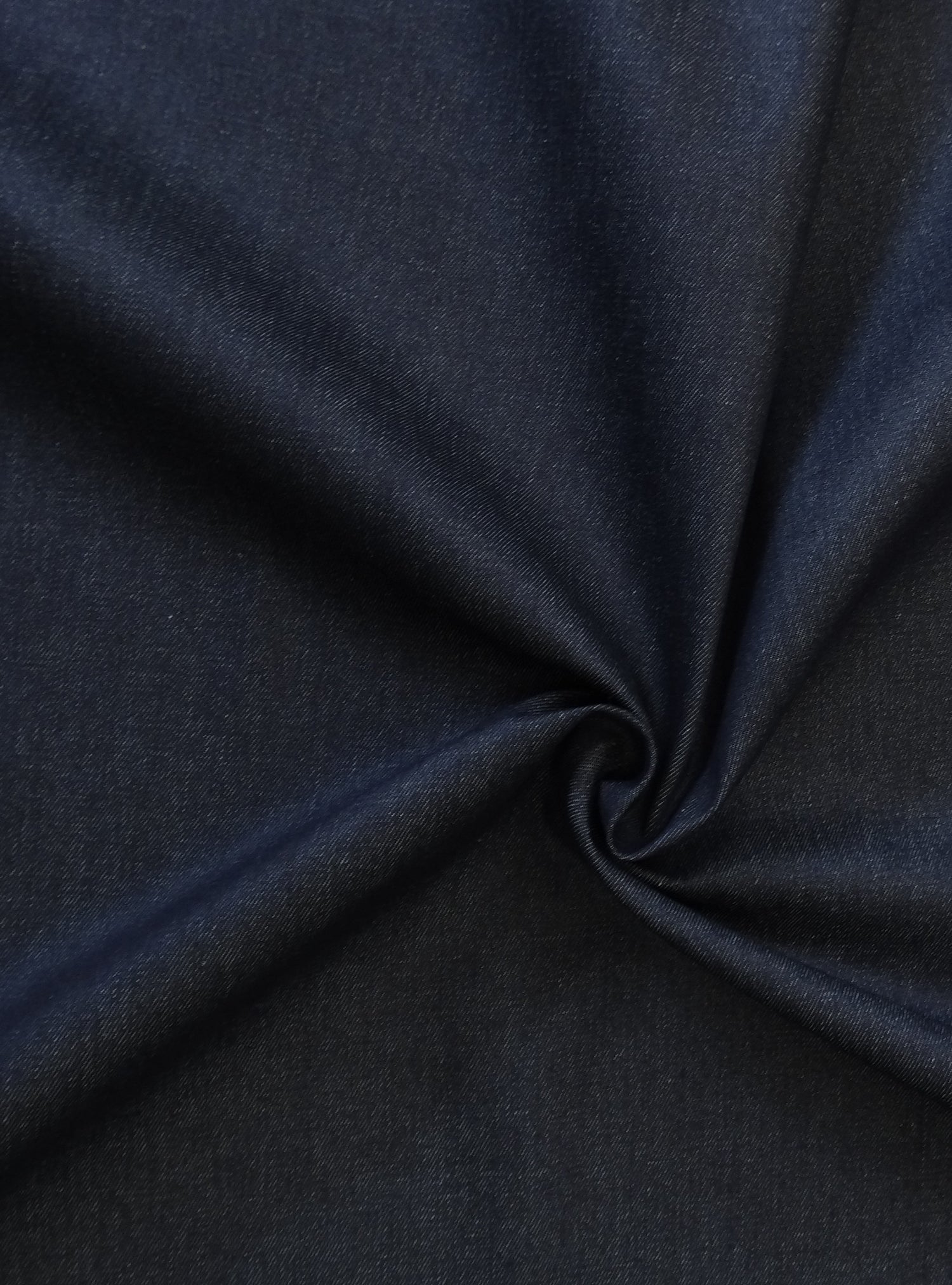 9oz denim fabric in a dark navy with a twist in the fabric showing how the light effects the colour of the fabric
