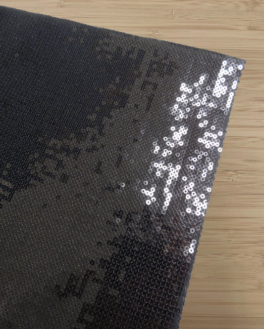 Folded Black Sequin fabric photographed from above on a wooden table