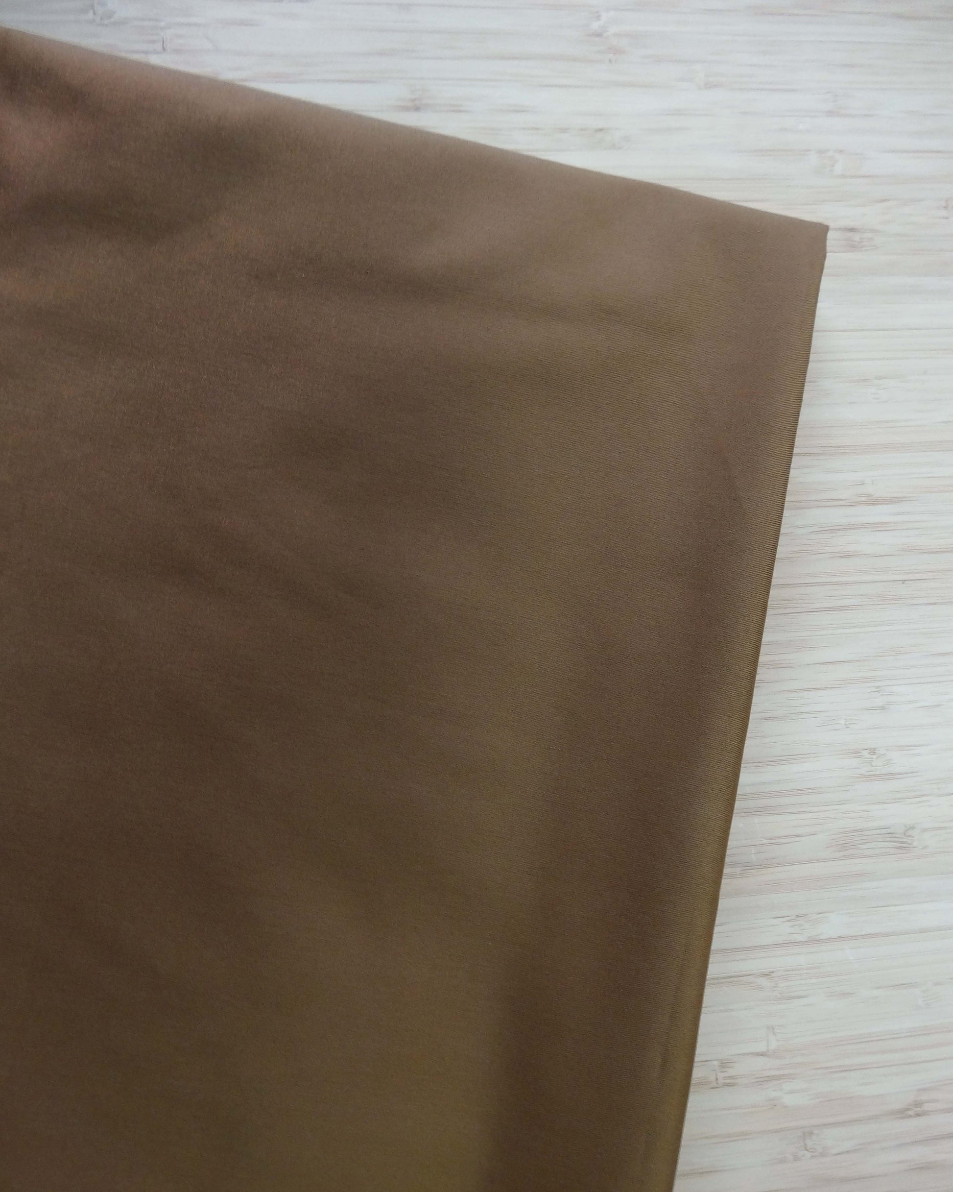 Brown cotton blended fabric folded and photographed on a light wooden surface