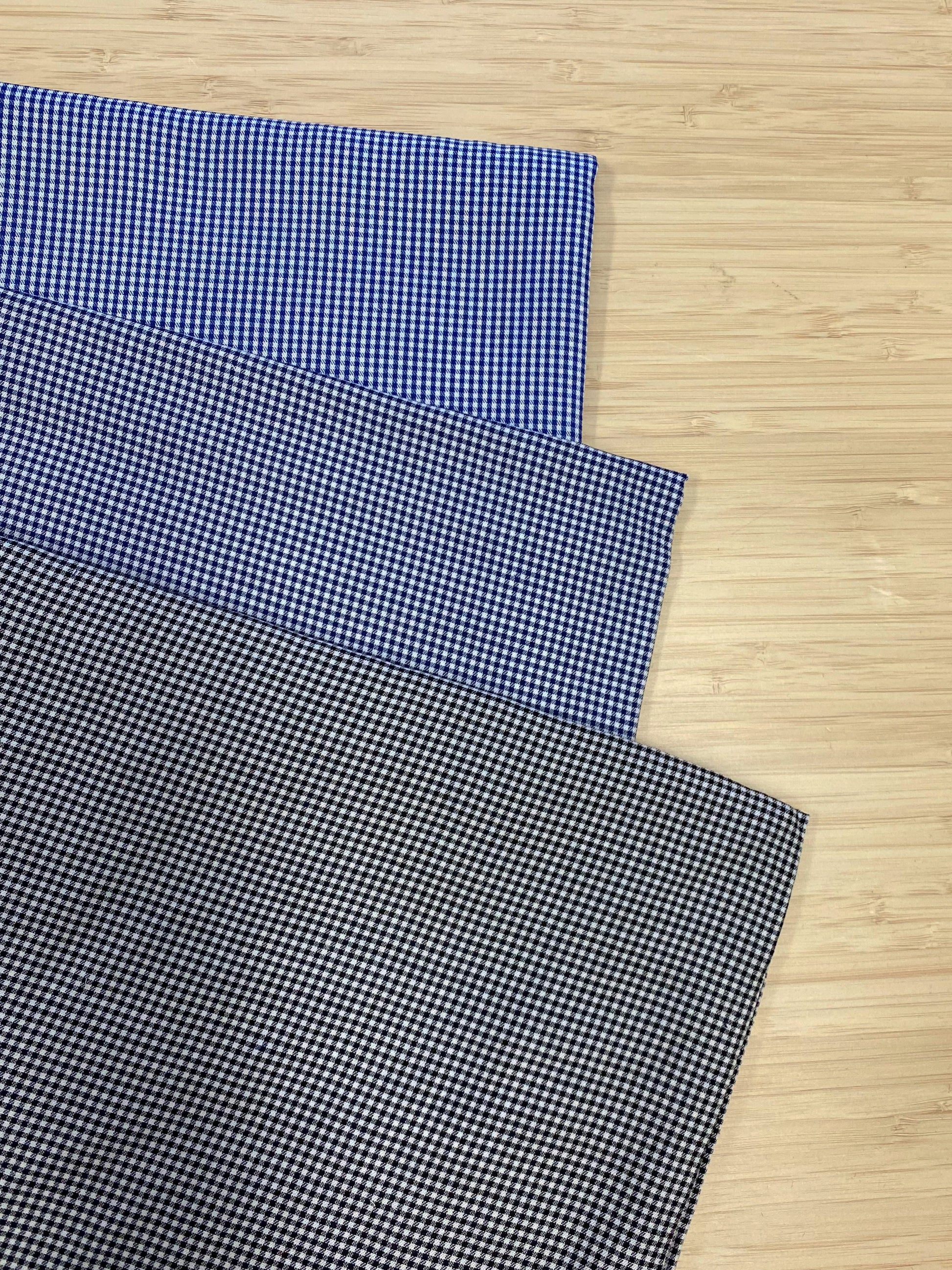 Photo of 3 different colours of Fine Detail Tencel Check fabric folded and stacked. photographed from above on a wooden table.
