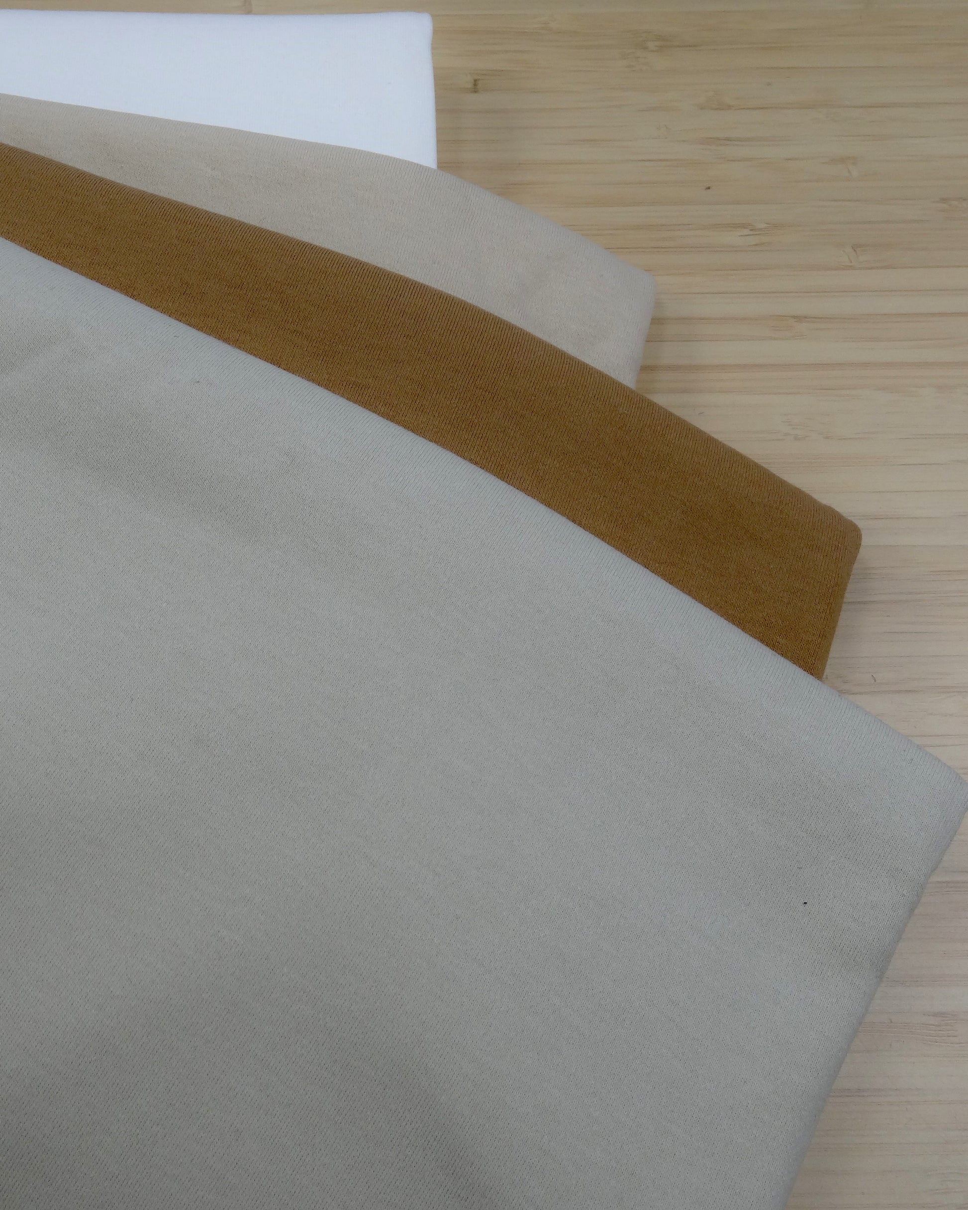 Four colours of heavy cotton  folded and stacked on a wooden table