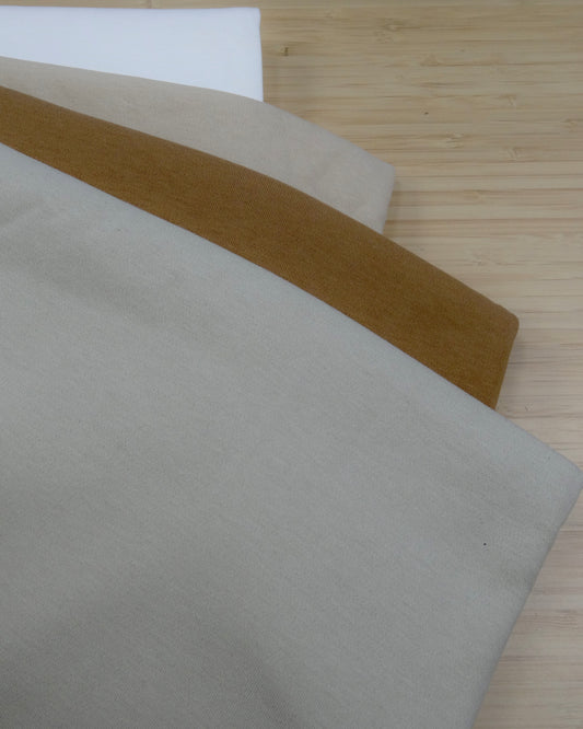 Four colours of heavy cotton  folded and stacked on a wooden table