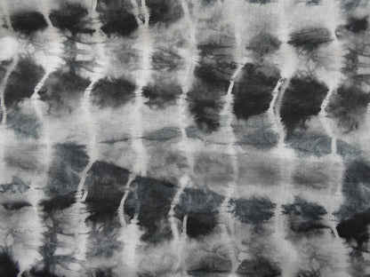 Photo of ripple design printed linen cotton blended fabric remnant in black/greys  on a wooden table. photographed from above.