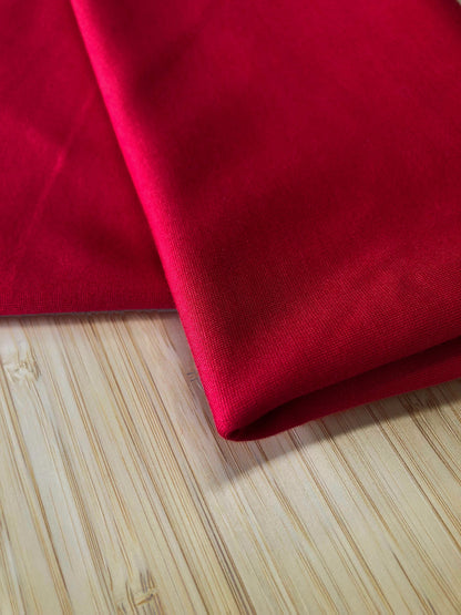 A red jersey fabric folded and photographed on a wooden table