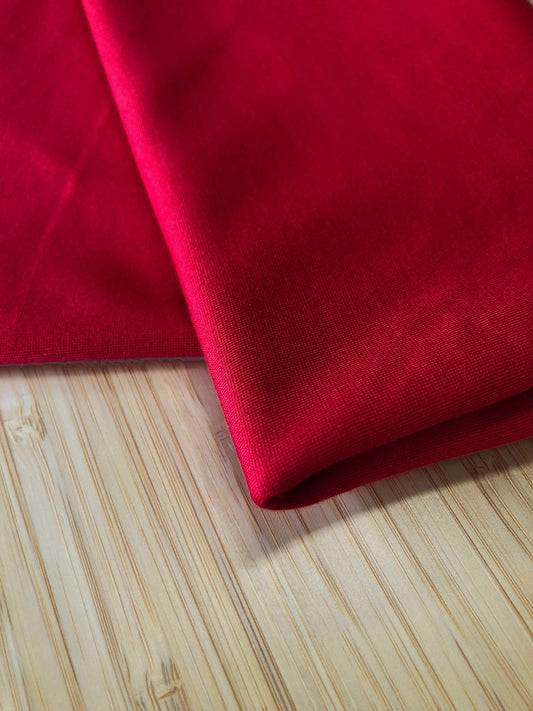 A red jersey fabric folded and photographed on a wooden table
