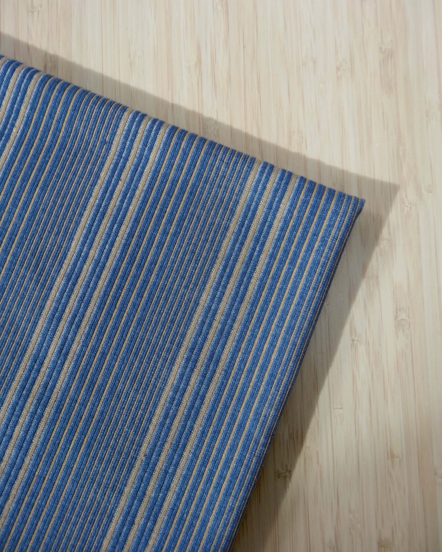 Blue and beige striped yarn dye ponte fabric photographed from above on wooden table
