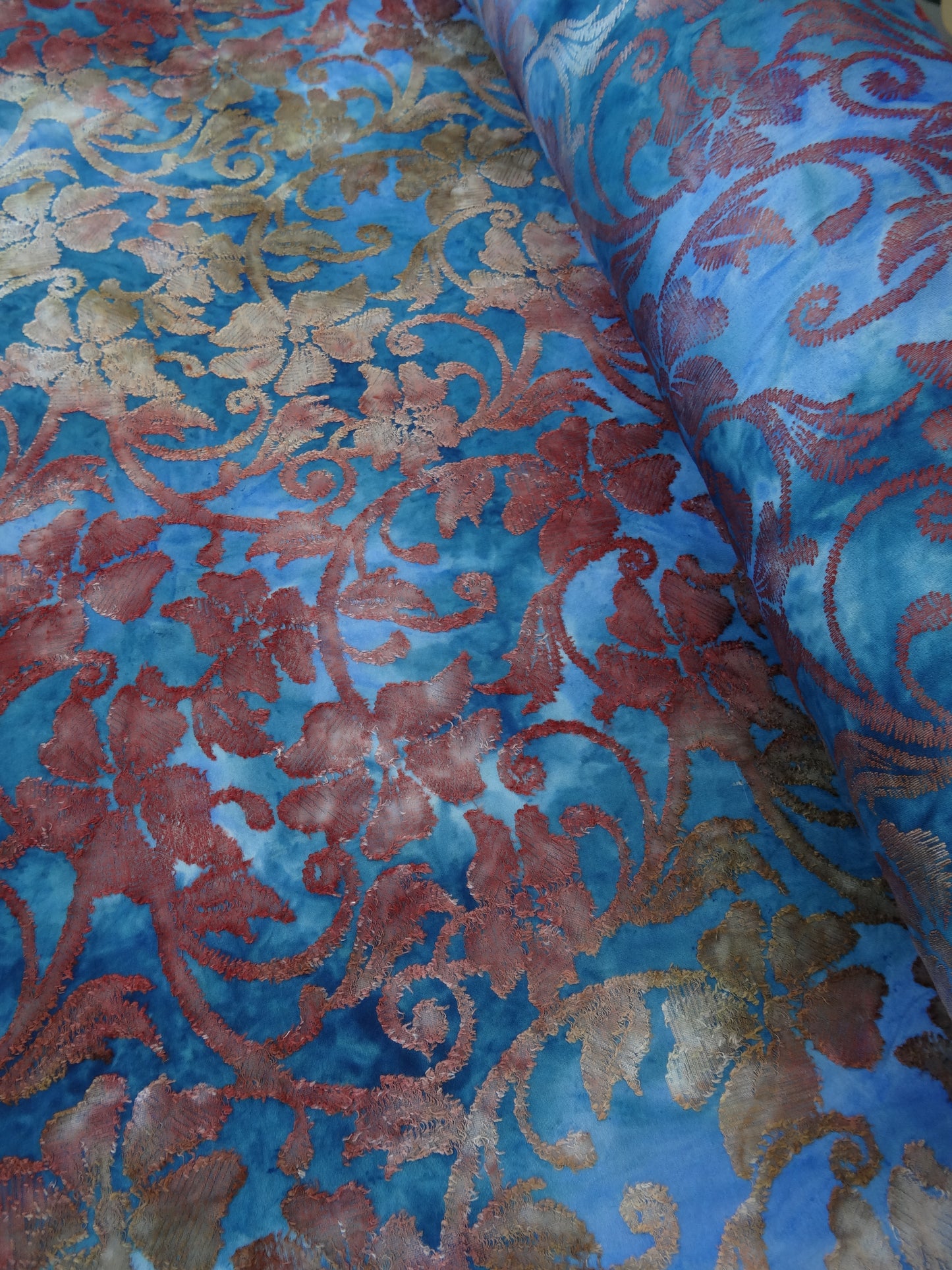 Blue based tie-dye fabric with red and ochre floral jacquard details