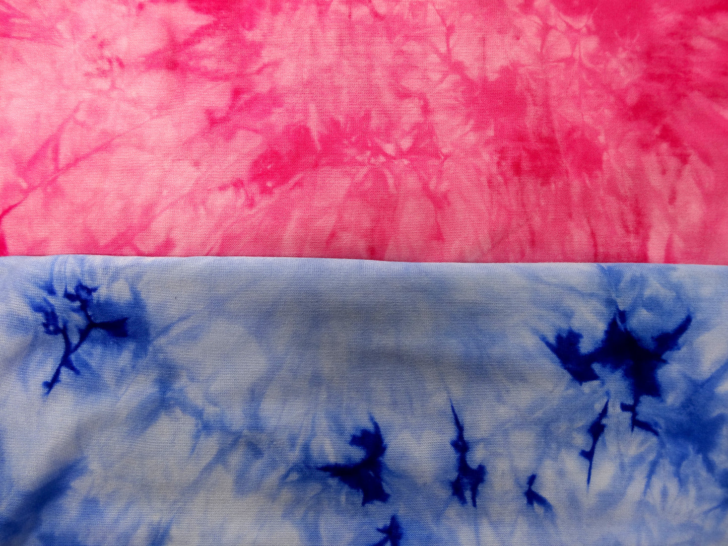 Close up of two colours of tie-dye fabric, one pink and white, the other blue and white.