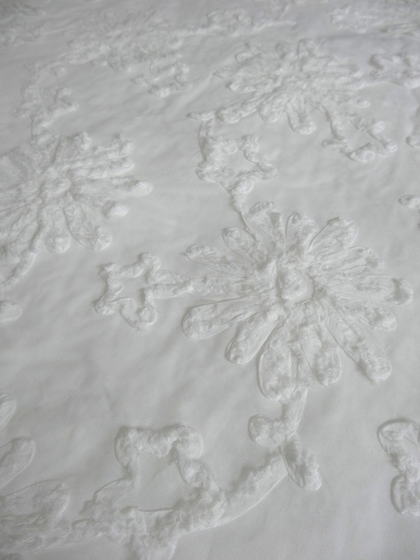 White 100% cotton fabric with white floral applique fabric shot close up