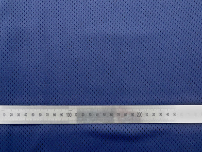 Close up of mesh fabric with metal ruler laid ontop to show spacing and size of the gaps in the mesh